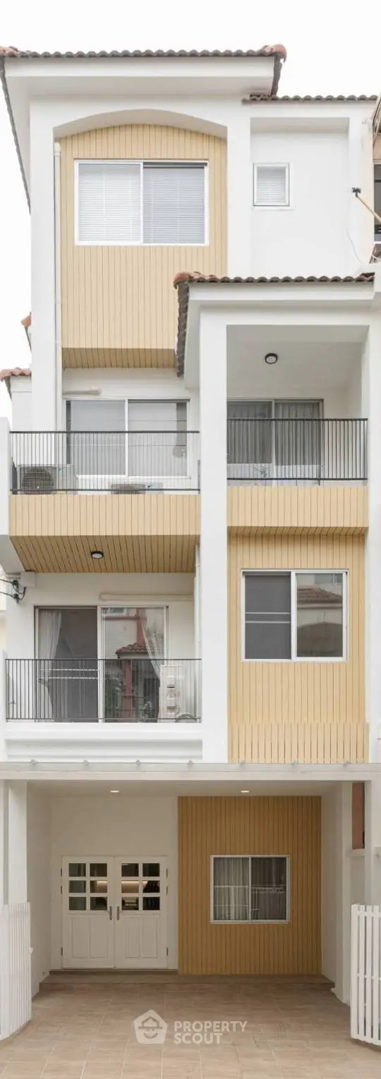 Modern multi-story townhouse with balconies and garage in a stylish urban setting.