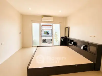 Spacious bedroom with modern bed frame and large window offering natural light.