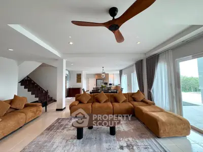Spacious modern living room with stylish brown sectional sofa and ceiling fan, open layout to dining area.