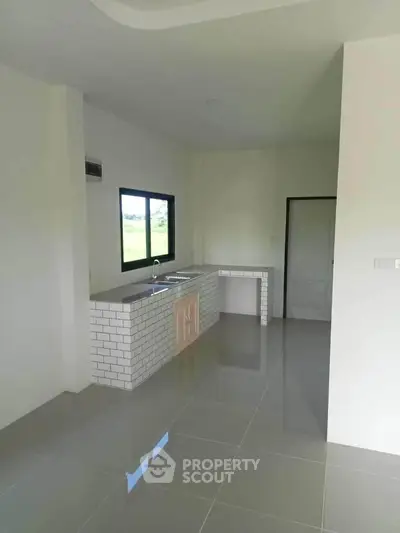 Modern minimalist kitchen with sleek tile flooring and large window view.
