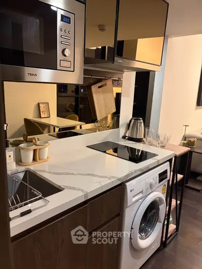 Modern kitchen with sleek appliances and integrated washing machine in compact space.