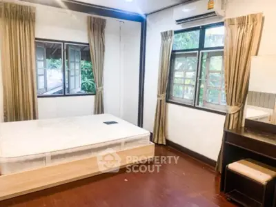 Cozy bedroom with large windows and wooden flooring, perfect for natural light lovers.