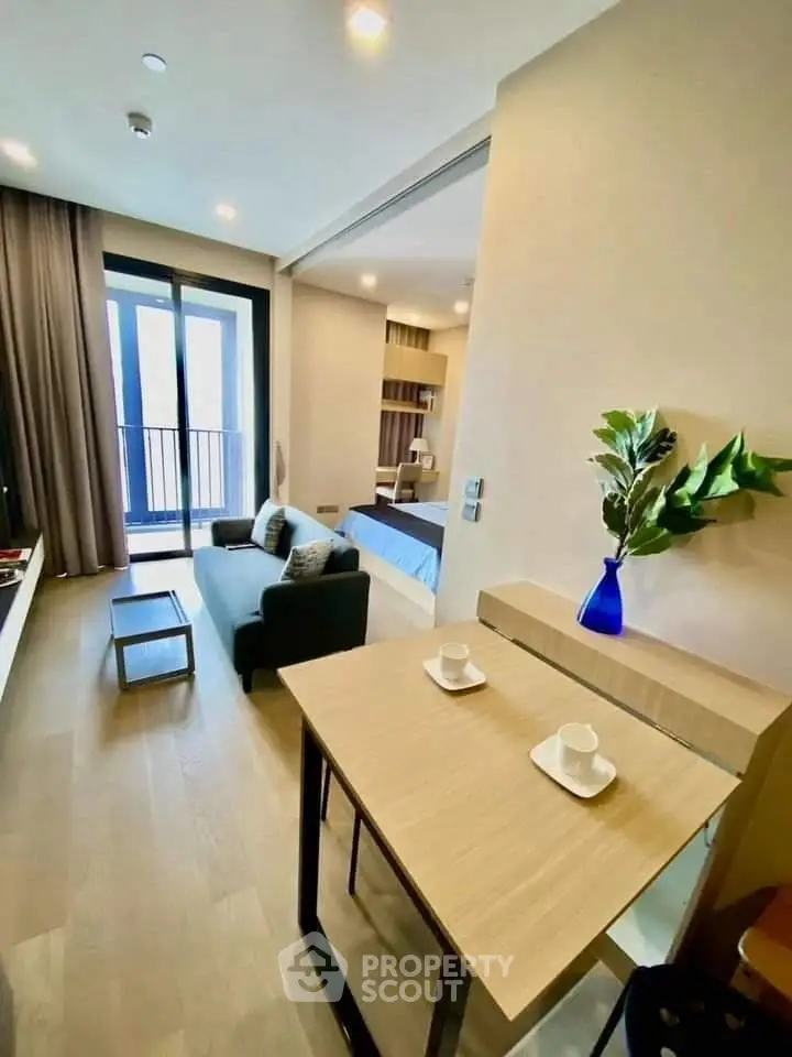 Modern open-plan living room with cozy seating and stylish decor, featuring a view of the balcony.