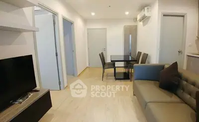 Modern living room with sleek furniture and dining area in open layout apartment.