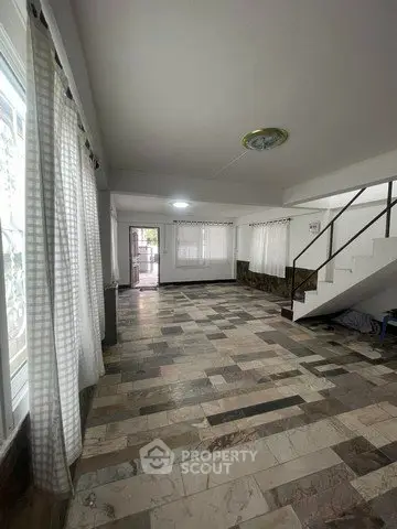 Spacious living room with large windows and stone tile flooring