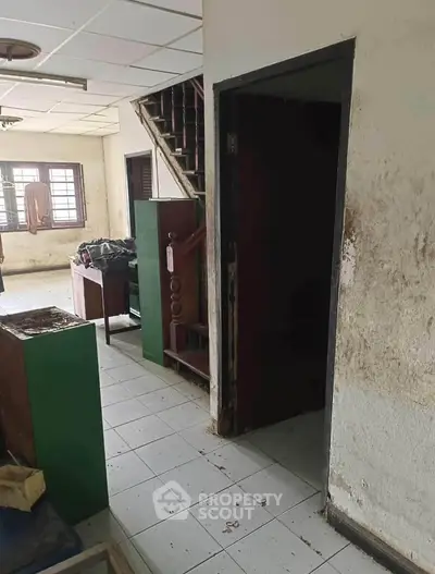 Spacious interior with staircase and natural light, ideal for renovation.