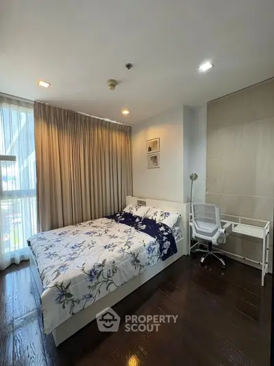 Cozy bedroom with modern decor and natural light, featuring a study desk and elegant curtains.