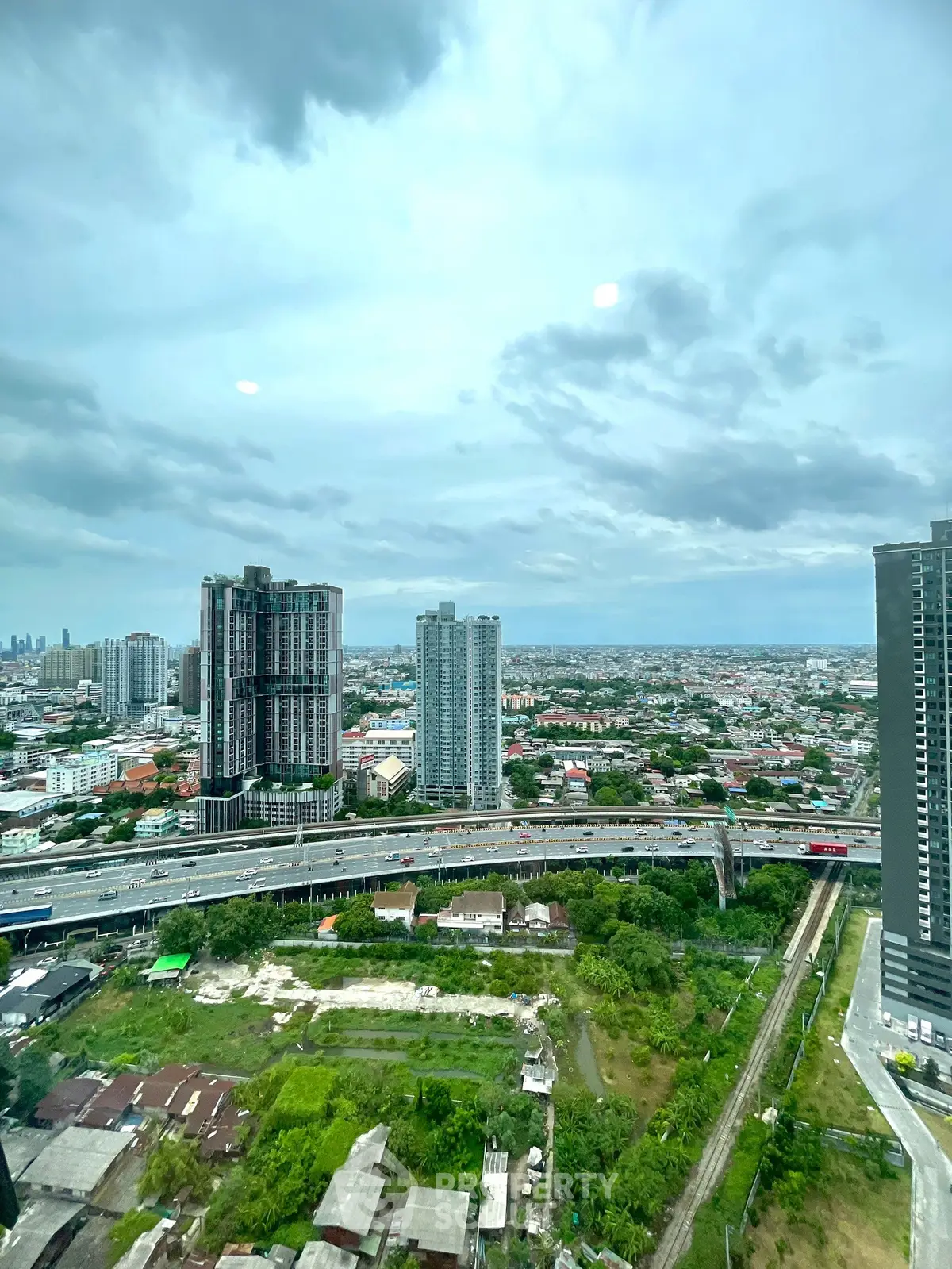 Stunning cityscape view from high-rise building showcasing urban skyline and lush greenery.
