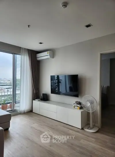 Modern living room with sleek TV setup and large window view.