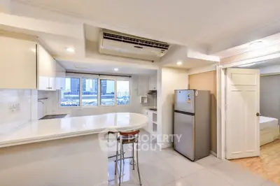 Modern kitchen with open layout and city view, featuring sleek appliances and breakfast bar.