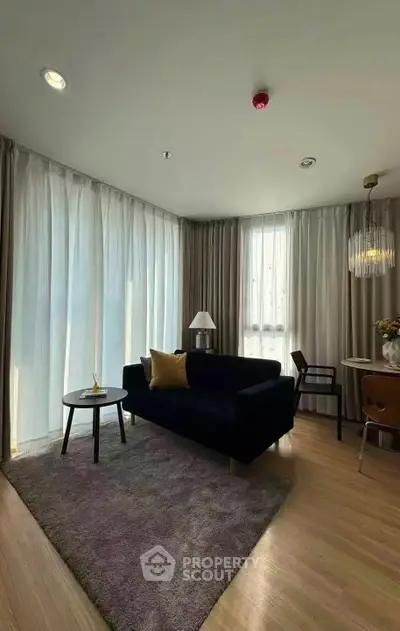 Elegant living room with modern decor, featuring a plush sofa, stylish lighting, and floor-to-ceiling windows.