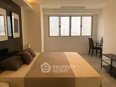 Spacious bedroom with city view and modern furnishings in high-rise apartment.