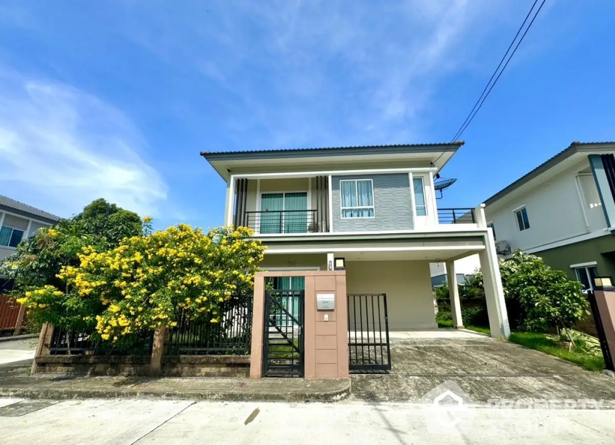 Modern two-story house with lush garden and spacious driveway in a serene neighborhood.