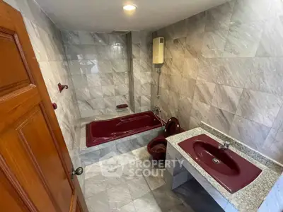 Luxurious bathroom with maroon fixtures and elegant marble tiles