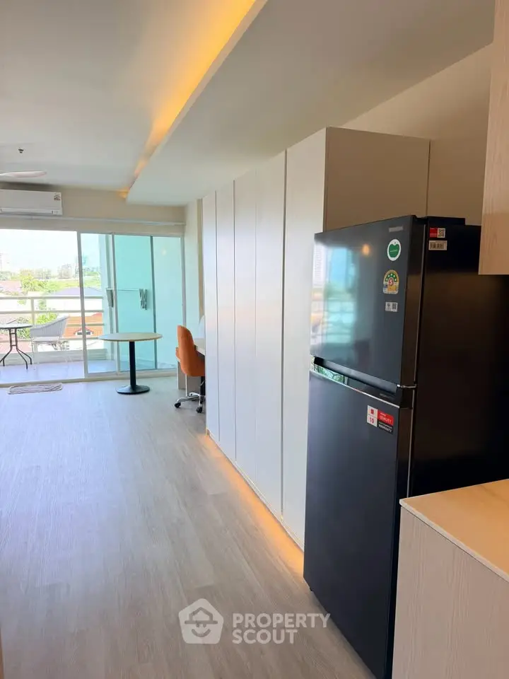 Modern apartment interior with sleek kitchen and spacious living area featuring a large balcony view.