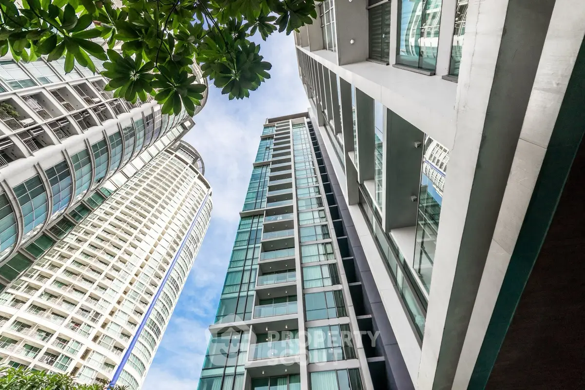 Stunning modern high-rise building with glass facade and lush greenery, perfect for urban living.