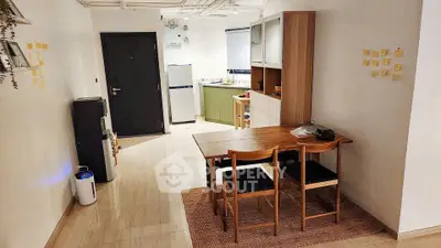 Modern dining area with wooden table and chairs, adjacent to a compact kitchen in an open layout.