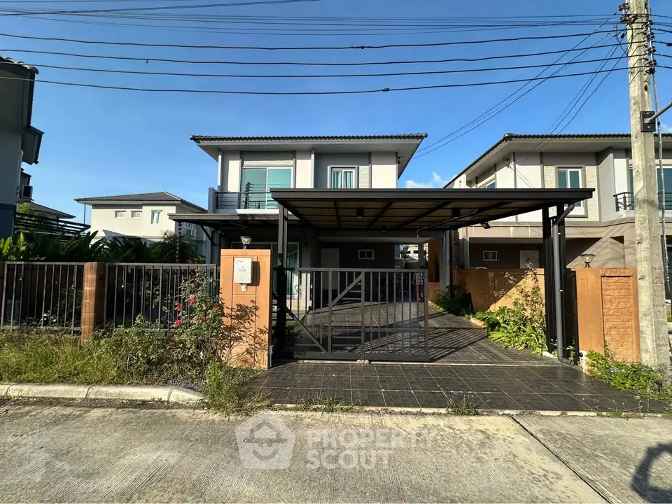Modern two-story house with gated driveway and lush garden in a serene neighborhood.