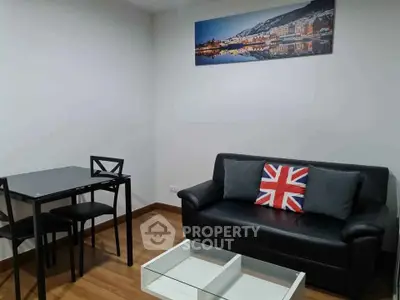 Cozy living room with modern black sofa and dining set, featuring a stylish wall art.