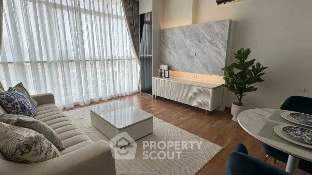 Elegant living room with large windows, stylish decor, and cozy seating area.