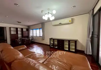 Spacious living room with leather sofa and modern lighting in a stylish apartment.