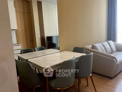Modern living room with elegant dining area and cozy sofa, featuring sleek design and warm tones.