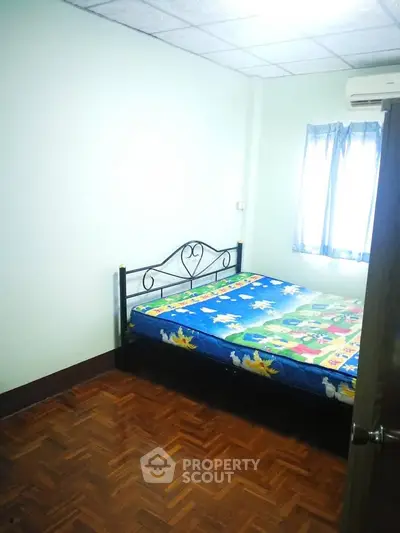 Cozy bedroom with parquet flooring and natural light, perfect for a restful retreat.