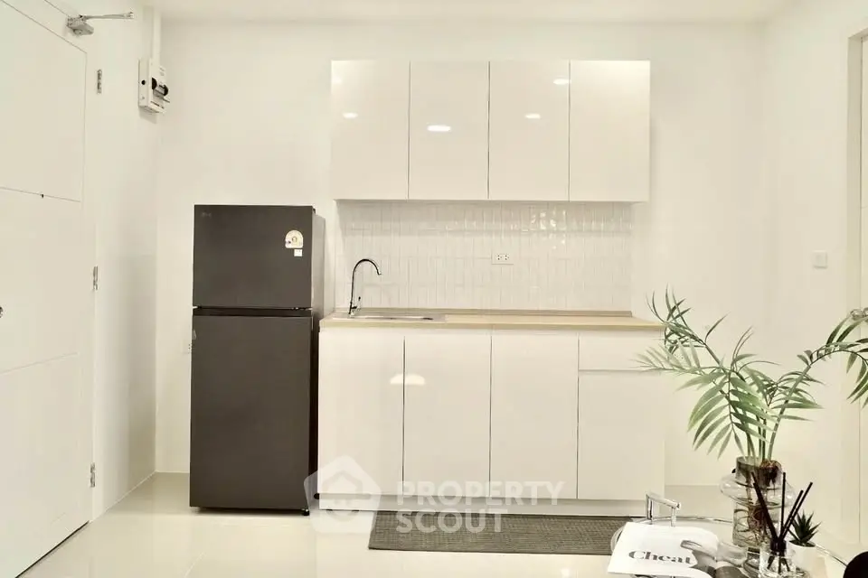 Modern minimalist kitchen with sleek white cabinets and black fridge