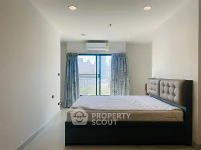Spacious bedroom with city view and modern furnishings in a high-rise apartment.