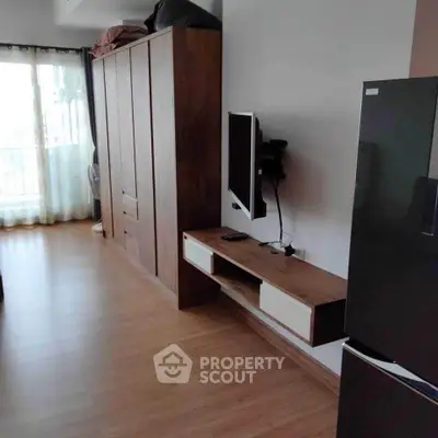 Modern apartment interior with wooden flooring, wall-mounted TV, and sleek refrigerator.