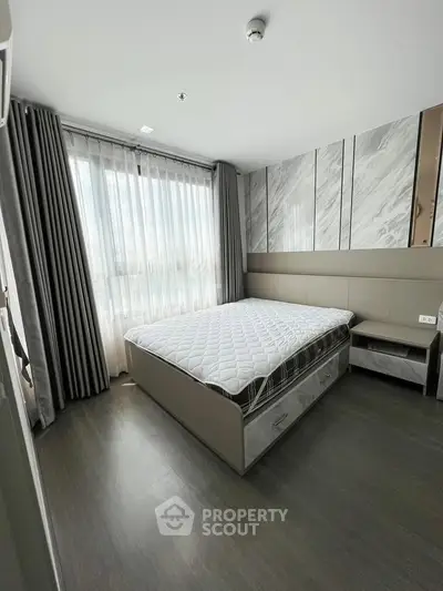 Modern bedroom with large window and stylish decor in a contemporary apartment.
