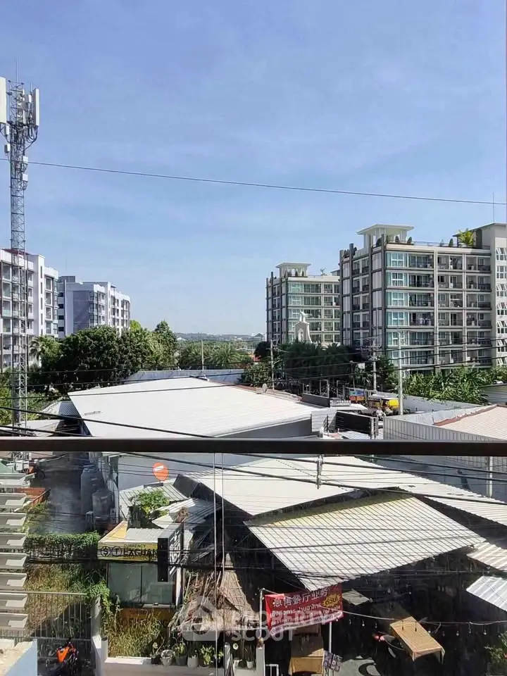 Stunning cityscape view from a modern balcony overlooking urban buildings and clear blue skies.