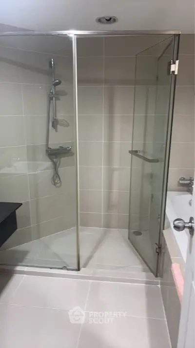 Modern bathroom with glass shower and bathtub in sleek design.