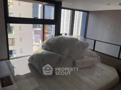 Modern bedroom with large windows offering city views, featuring a neatly made bed and contemporary design.