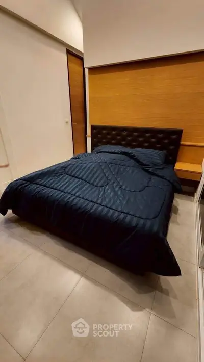 Modern bedroom with stylish bed and wooden accent wall, perfect for a cozy retreat.