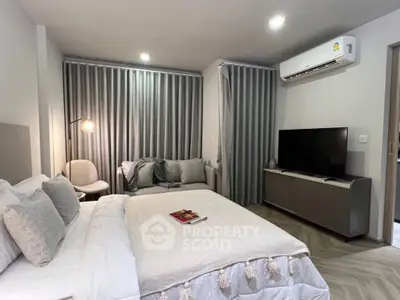Modern bedroom with cozy decor and air conditioning, featuring a stylish TV setup.