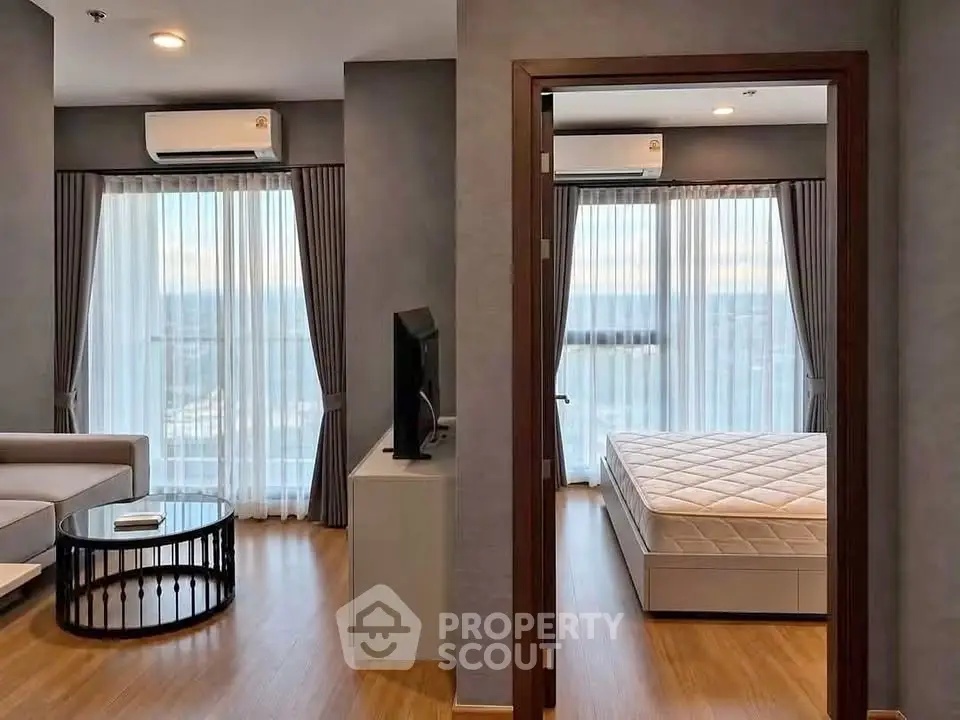 Modern apartment with spacious living room and cozy bedroom, featuring large windows and elegant decor.