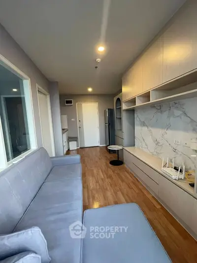 Modern living room with stylish furniture and built-in storage, featuring elegant wood flooring and bright lighting.