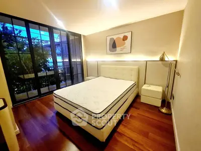 Elegant bedroom with modern decor and large windows overlooking lush greenery.