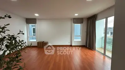 Spacious empty living room with hardwood floors and balcony access