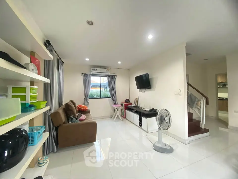 Spacious living room with modern decor and natural light, featuring a cozy sofa and wall-mounted TV.