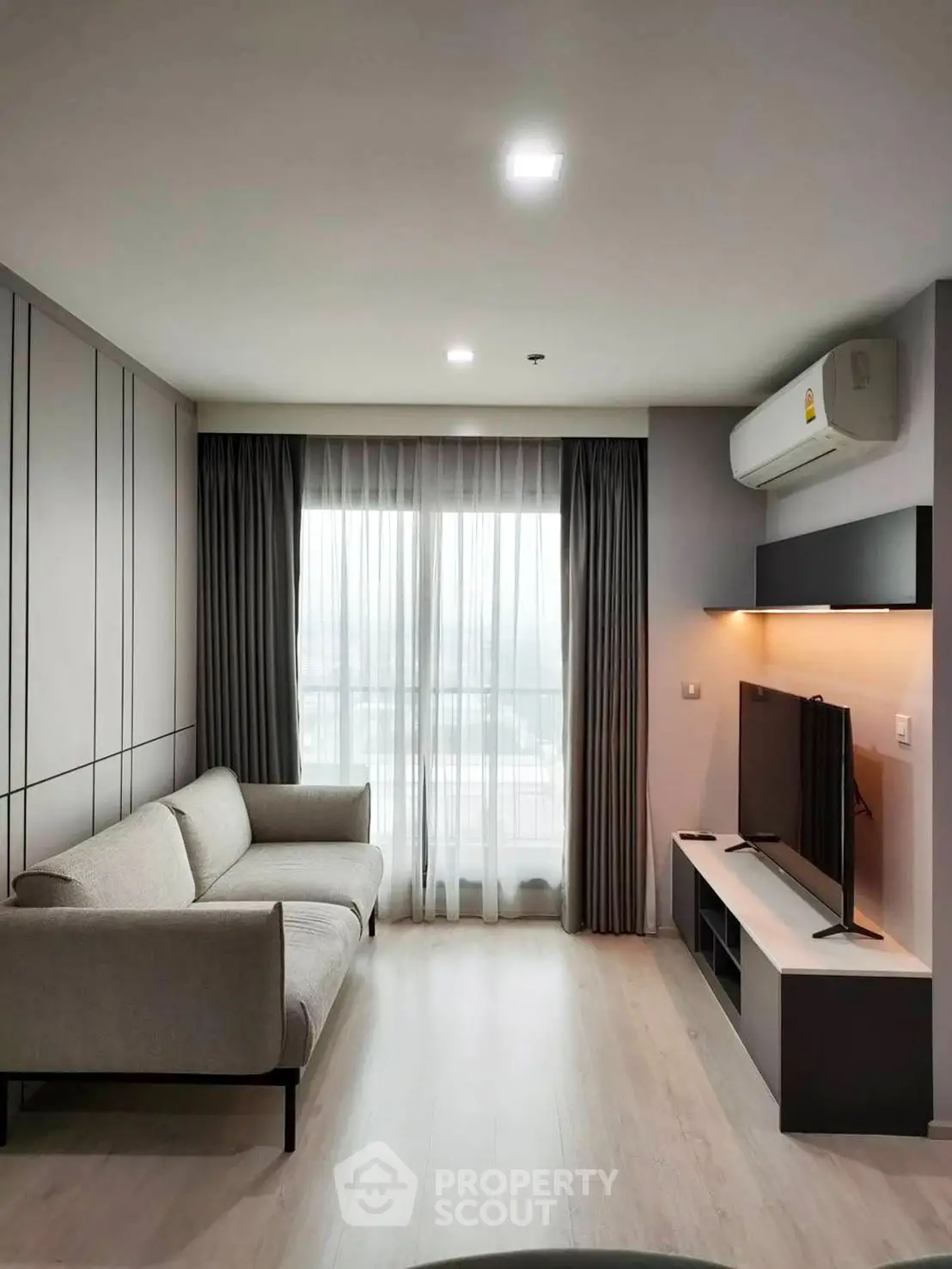 Modern living room with sleek design, featuring a cozy sofa, large TV, and floor-to-ceiling windows with city view.