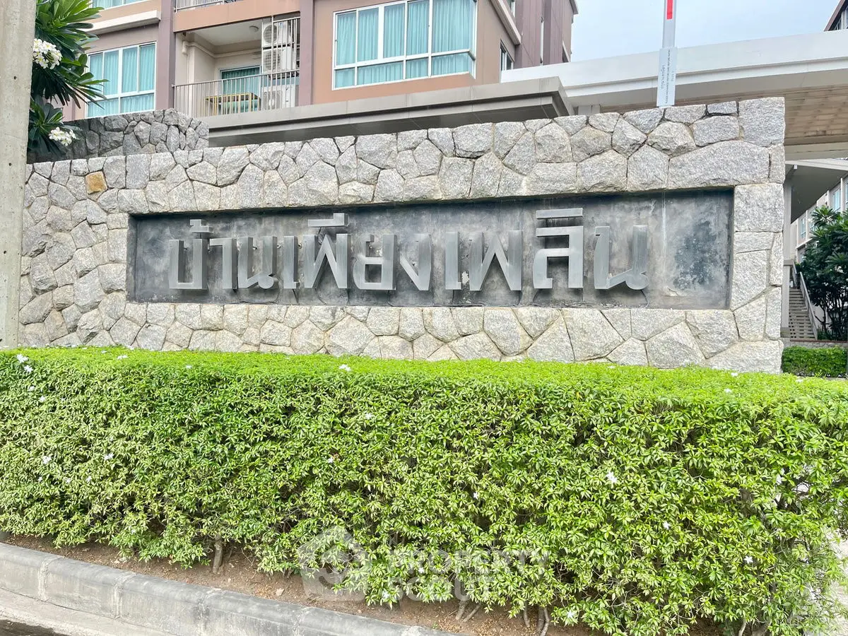 Elegant stone entrance of a modern residential building with lush greenery.