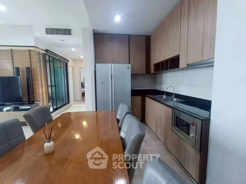 Modern kitchen with sleek wooden cabinets and dining area in open layout.