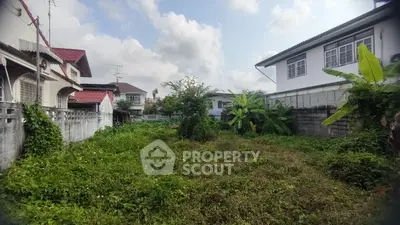 Spacious residential plot with lush greenery and neighboring houses