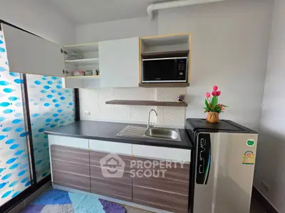 Modern compact kitchen with sleek cabinets, microwave, and mini fridge in a cozy apartment.