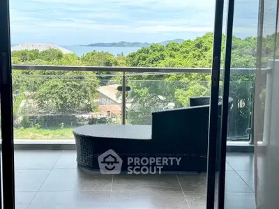 Stunning balcony view with lush greenery and ocean in the background, perfect for relaxation.