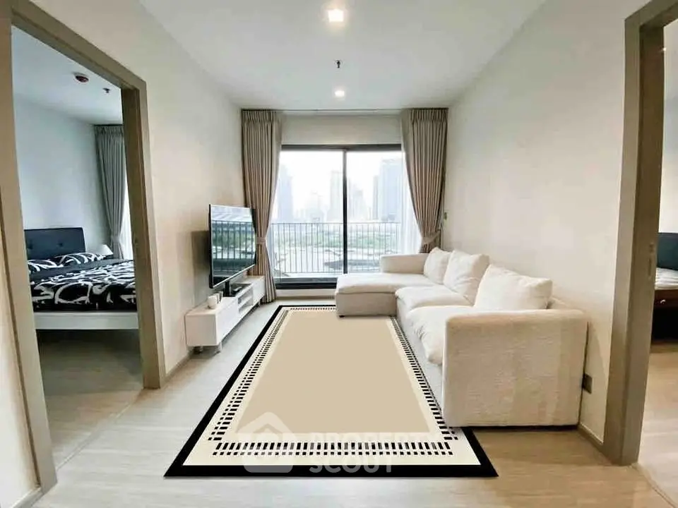 Modern living room with large sofa and city view, adjacent to stylish bedroom.