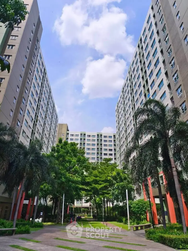 Stunning view of modern high-rise apartment buildings with lush greenery and clear blue sky.