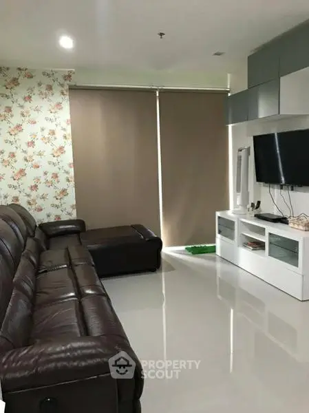 Modern living room with leather sofa and wall-mounted TV, featuring floral accent wall and sleek cabinetry.